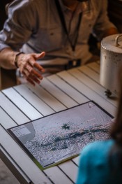 Photo prise lors de la Nuit européenne des chercheurs 2024 représentant la main d'un chercheur à côté d'une carte du sud-ouest avec les impacts sismiques de la région